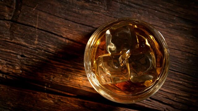 Super Slow Motion Shot of Droplets Falling into Glass of Whiskey with Ice Cubes at 1000fps.
