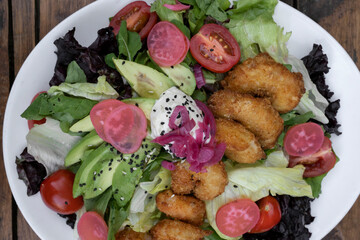 Sea salad background. Closeup view of a fresh salad with lettuce, cherry tomatoes, avocado, radish and onion pickles, seeds and cream cheese, in a white dish.