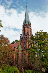 Fototapeta na wymiar Catholic church among the autumn trees in Myslenice, Poland. European sights