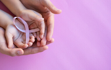 Adult and child hands holding pink ribbons, Breast cancer day