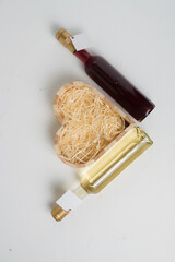 two 250 ml bottles of red and white wine with blank label on light background, copy space. Heart...