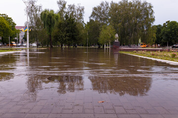 Soft focused shot of town streets flooded by heavy rain. Thunderstorm consequences. Big puddle with...