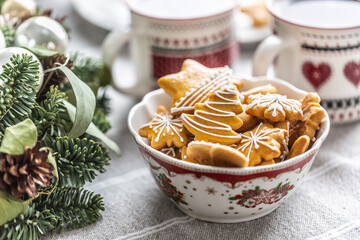 A bowl full of Christmas gingerbread on the table led an Advent wreath and two cups with coffee, punch or tea