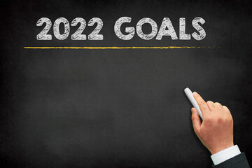 2022 Goals new year. A male hand writing new year golas on chalkboard