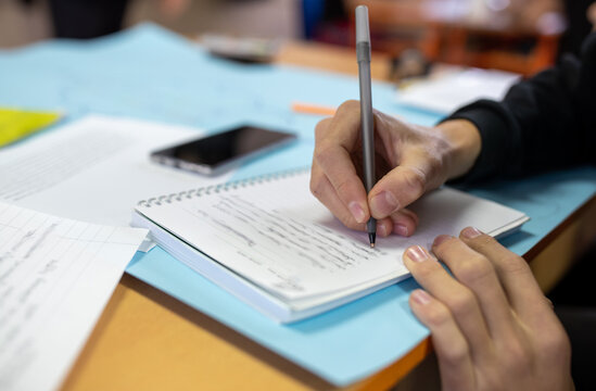 Student writing notes on desk in classroom