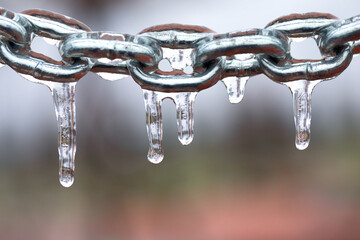 Icicles on a chain, frosted metal on a light background.