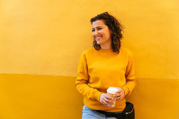 Cheerful young woman with cup of coffee in street