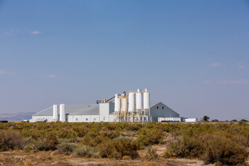Industrial facility with large white silos in the middle of a dessert