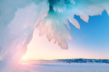 Ice cave on Baikal lake in winter. Blue ice and icicles in the sunset sunlight. Olkhon island, Baikal, Siberia, Russia. Beautiful winter landscape.