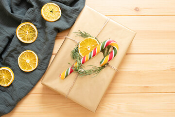 Christmas wrapped gift in eco style. Golden box with Christmas tree, dry orange slice and traditional candy cane. Top view. Best wishes, gift wrapping idea concept. Step-by-step instruction. 