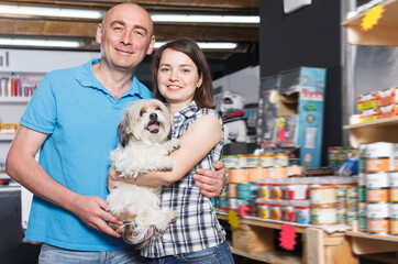 Portrait of nice family couple with dog selecting vet preserves in petshop
