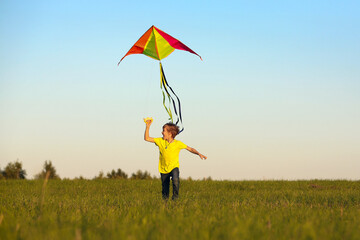 The boy launches a kite. Summer day. Sunny.The boy in a yellow t-shirt with a kite. The joy of relaxation and emotions.