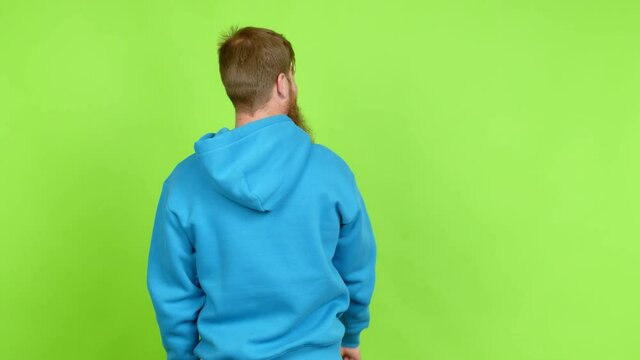 Redhead man with long beard pointing back with the index finger over isolated background