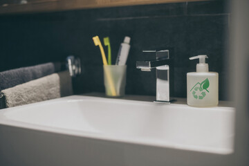 Closeup view of a sink with towels, toothbrush and soap dispenser. Modern environment bathroom...