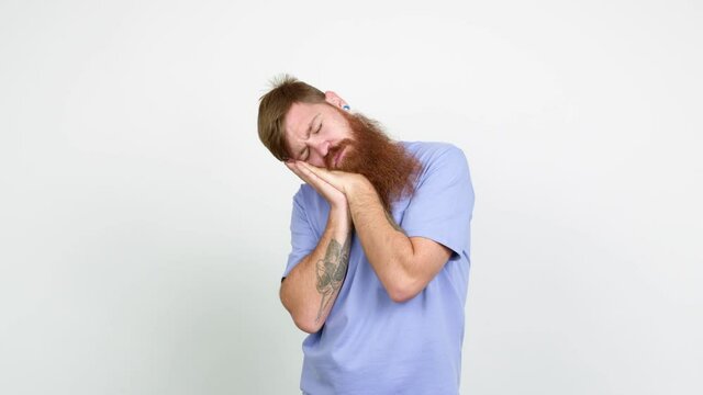 Redhead man with long beard making sleep gesture. Adorable and sweet expression over isolated background