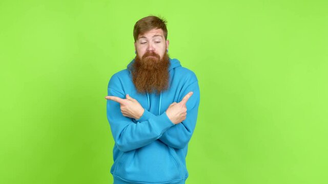 Redhead man with long beard pointing to the laterals having doubts over isolated background