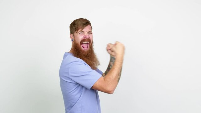 Redhead man with long beard celebrating a victory over isolated background