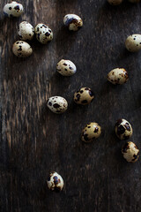 Quail eggs scattered on a wooden surface from above