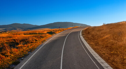 Paved road in the mountains. Autumn landscape at sunset.