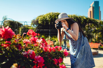 Young woman taking photos with a professional camera at park during vacations