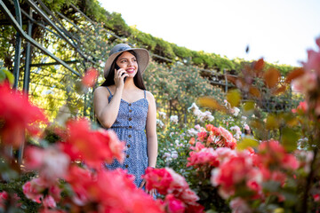 Young woman talking on the phone at park during spring summer season in vacations