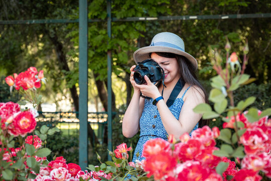 Young woman taking photos with a professional camera at park during vacations