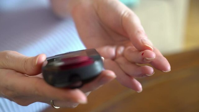 Female sugar diabetic patient measuring blood glucose level with a glucometer at home. Health care, diabetic lifestyle. Close-up.