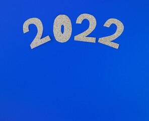 silver glitter shapes of numbers 2022 on blue background, minimalism new year concept. Place for text