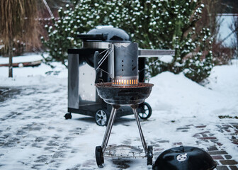 Burning charcoal and fire in barbecue chimney on brazier. Winter grilling - Powered by Adobe
