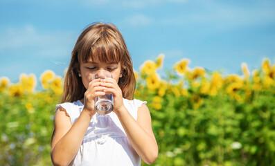 The child drinks water from a glass. Selective focus.