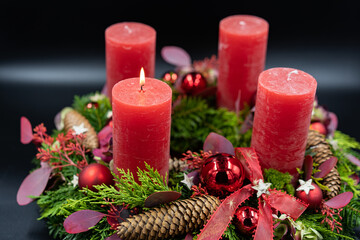Close up of beautiful advent wreath with one burning candle on black background