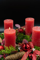Vertical low angle view of beautiful advent wreath with one burning candle on black background