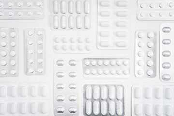 White pills and capsule, medicine tablet in foil blister pack with on white background....