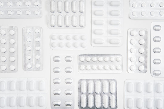 White pills and capsule, medicine tablet in foil blister pack with on white background. Minimalistic geometric medical background with Variety of pills and capsules.