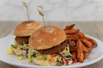 Artistic presentation of crispy fried crab cake sliders on buttery buns and served with crunchy french fries