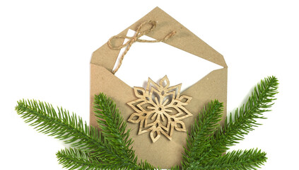 White sheet of paper in a kraft paper envelope decorated with a wooden snowflake.
