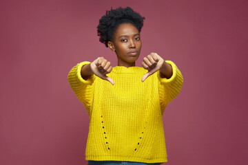 Dissatisfied young african american girl thumbs down gesture, negative feedback, dislike,...