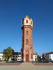 Fototapeta na wymiar Brick restored water tower in the Art Nouveau architectural style rises on the central square of the ancient city of Staraya Russa, Novgorod region. Industrial architecture of the early XX century 