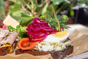 Traditional Danish sandwich, Smerrebred with salted salmon, pickled onion, egg and salad on rye bread.