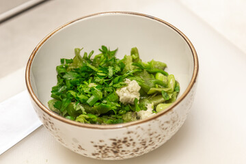 Chopped greens - parsley, cilantro, dill, onion and garlic are in a bowl