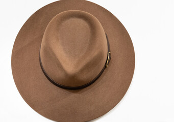 Classic cowboy brown felt hat with strap and copper closure on white background. Top view
