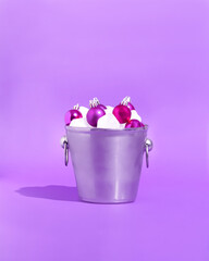 An ice bucket of Christmas ornaments in a purple background