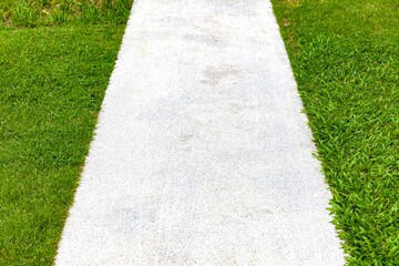 Long concrete walkway in the summer green garden