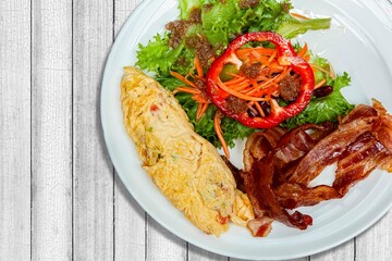 Western breakfast, scrambled eggs, bacon and fresh vegetables with tomato sauce
