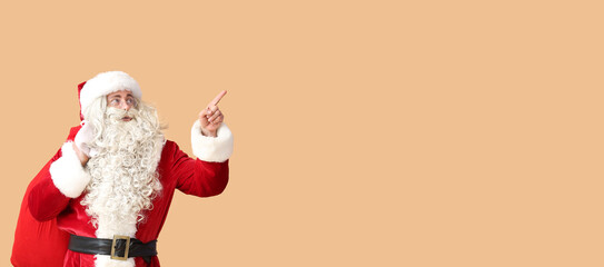 Santa Claus with bag pointing at something on beige background with space for text