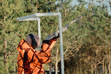 Hunter in camouflage with rifle in winter forest. Hunt concept. Man securing a reserve, on a snowy day. Hunter takes aim from a gun in the snowy forest