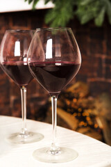 Pair of glasses with red wine against the background of a burning fireplace.
