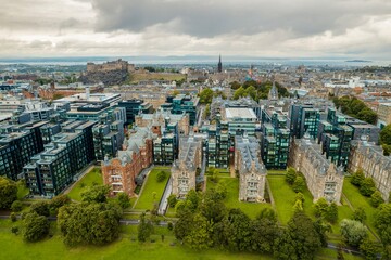 Stunning aerial view of Edinburgh in Scotland, with the castle dominates the skyline, casting its shadow over the surrounding historic town occupying commanding position on volcanic crag with cliffs
