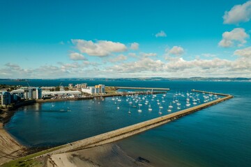 Fototapeta premium Iconic marina, located along the east coast of Scotland, presents a stunning view of the sea. Taking an aerial view of the marina, image displays a stunning image of the marina large yachts and boats