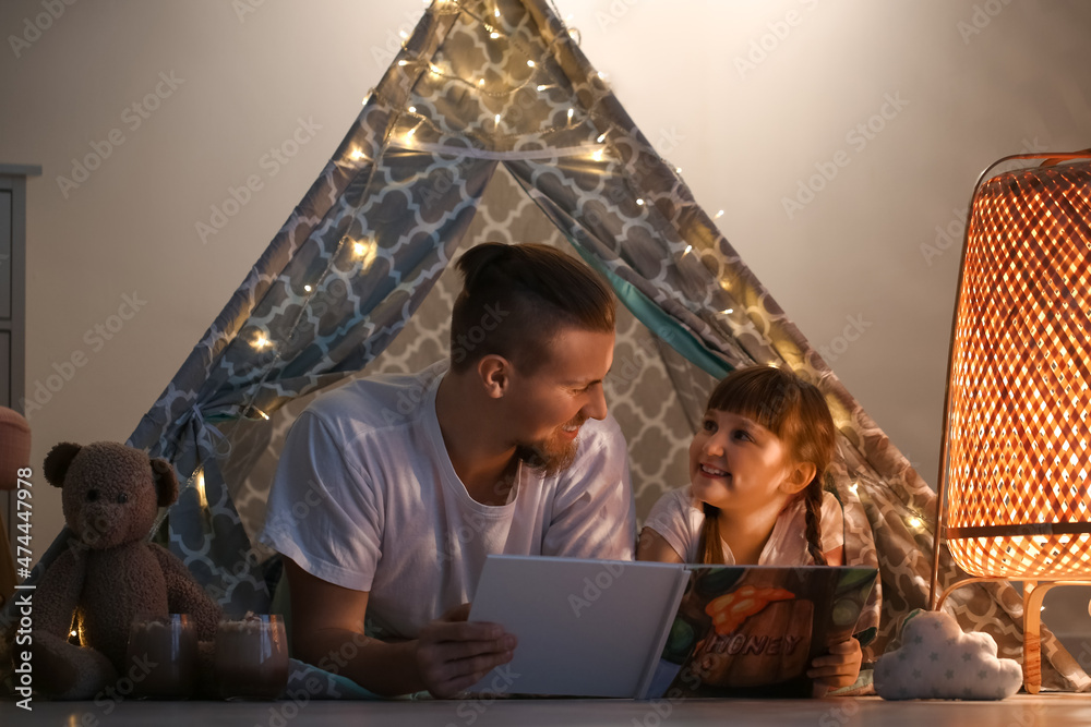 Sticker happy daughter and father reading book late in evening at home